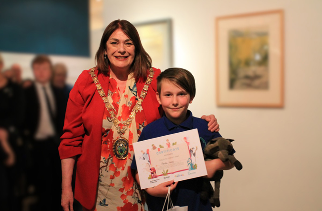 The former Mayor of Rugby, Cllr Maggie O'Rourke, with Martha, the overall winner of Rugby Art Gallery and Museum's book cover art competition.