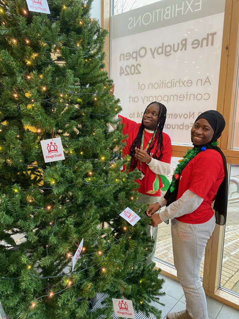 Tanya Chikeya (left) and Adama Darame (right), from Rugby College's King's Trust team, decorating the Christmas tree at Rugby Art Gallery and Museum.